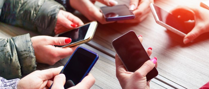 A group of teenagers holding mobile phones