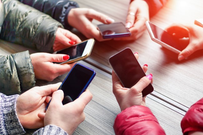 A group of teenagers holding mobile phones