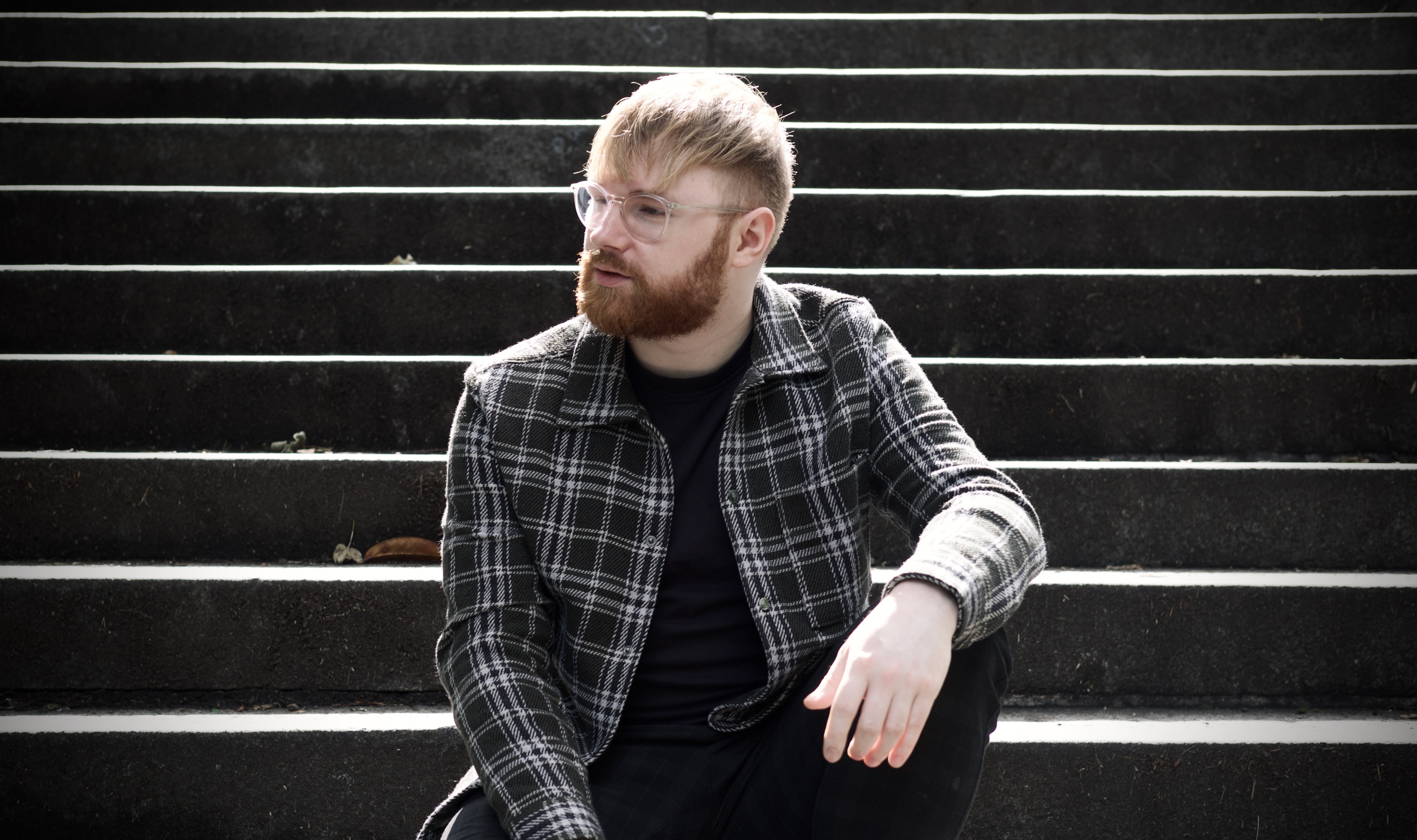 A man sitting on a set of steps outside, looking off camera