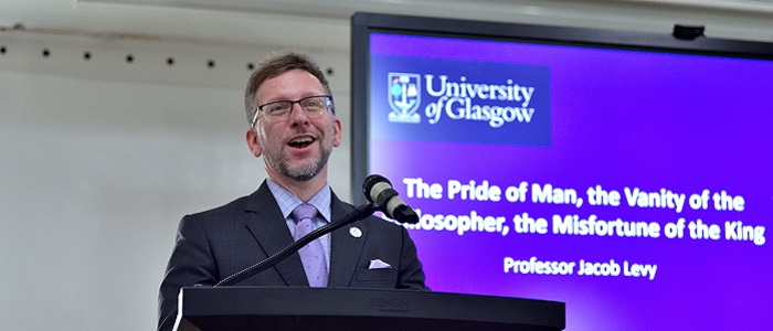 Jacob Levy standing in front of a podium and a presentation slide behind Source: Charlotte Morris