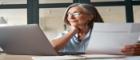 An older female employee sits at her desk, she is smiling