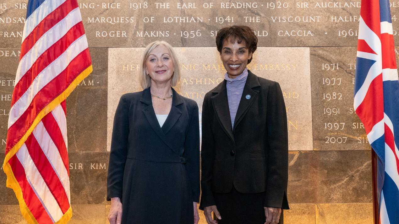 Sara Carter and Cecilia Rouse standing with foundation stone behind them and the UK and USA flags on either side Source: Charlotte Morris