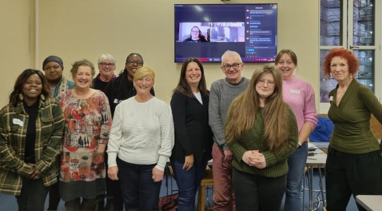 SIPHER Community Panel Members standing in front of a screen smiling to camera