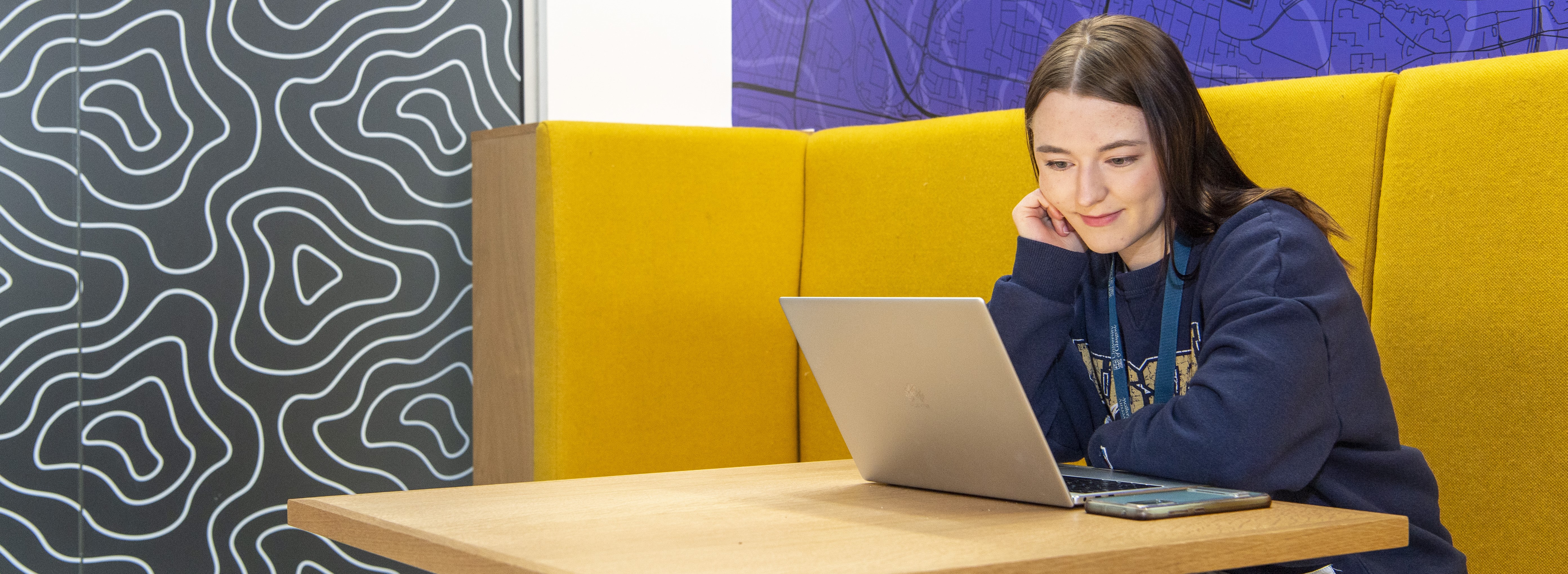 person sitting at table looking at laptop