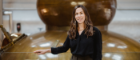 Alumna Jennie Baernreuther stands before a gold whisky distillery machine