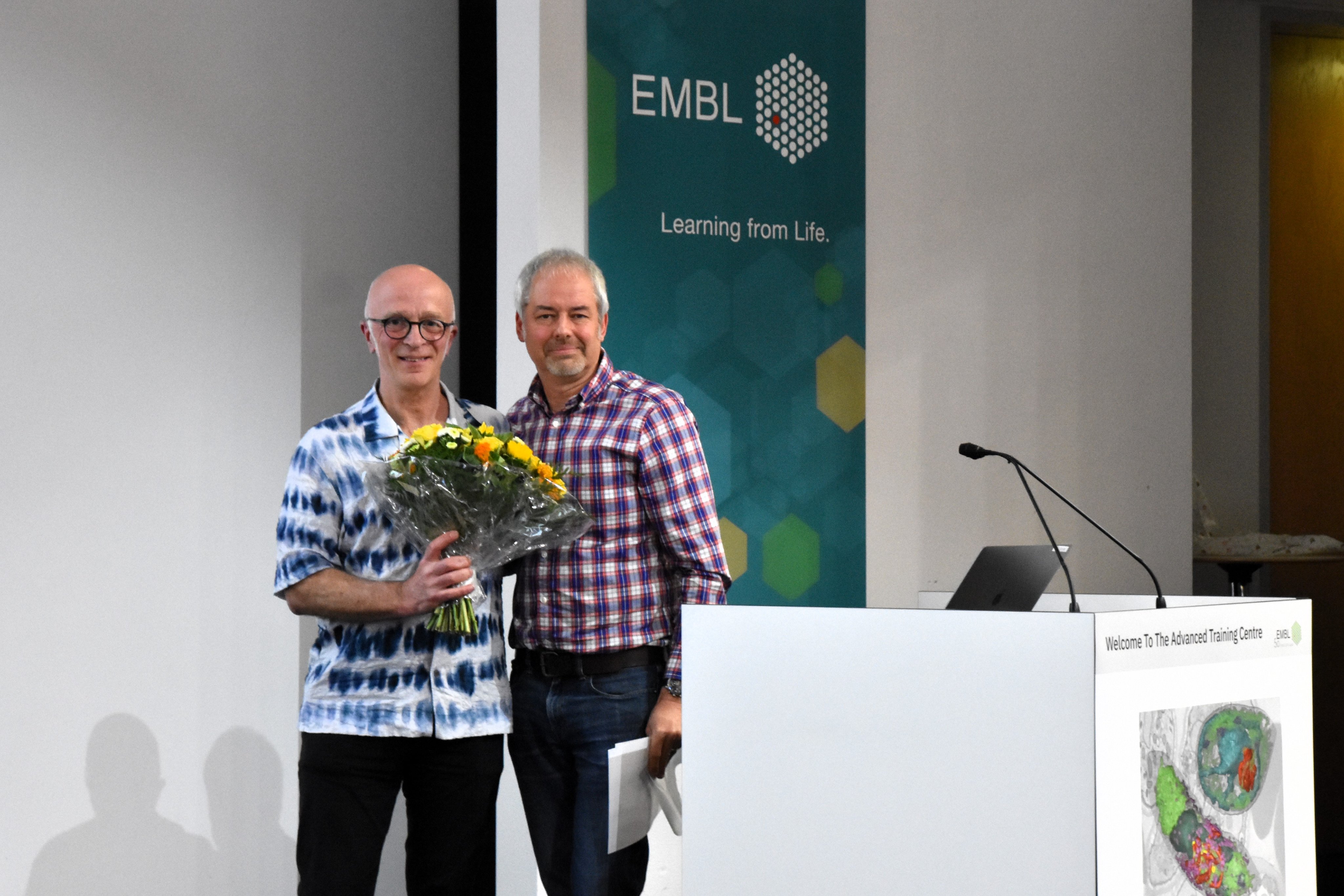 Professor Andrew Waters on stage being presented with a bouquet of flowers