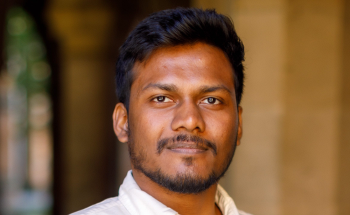 A man in a white shirt smiles serenely at the camera