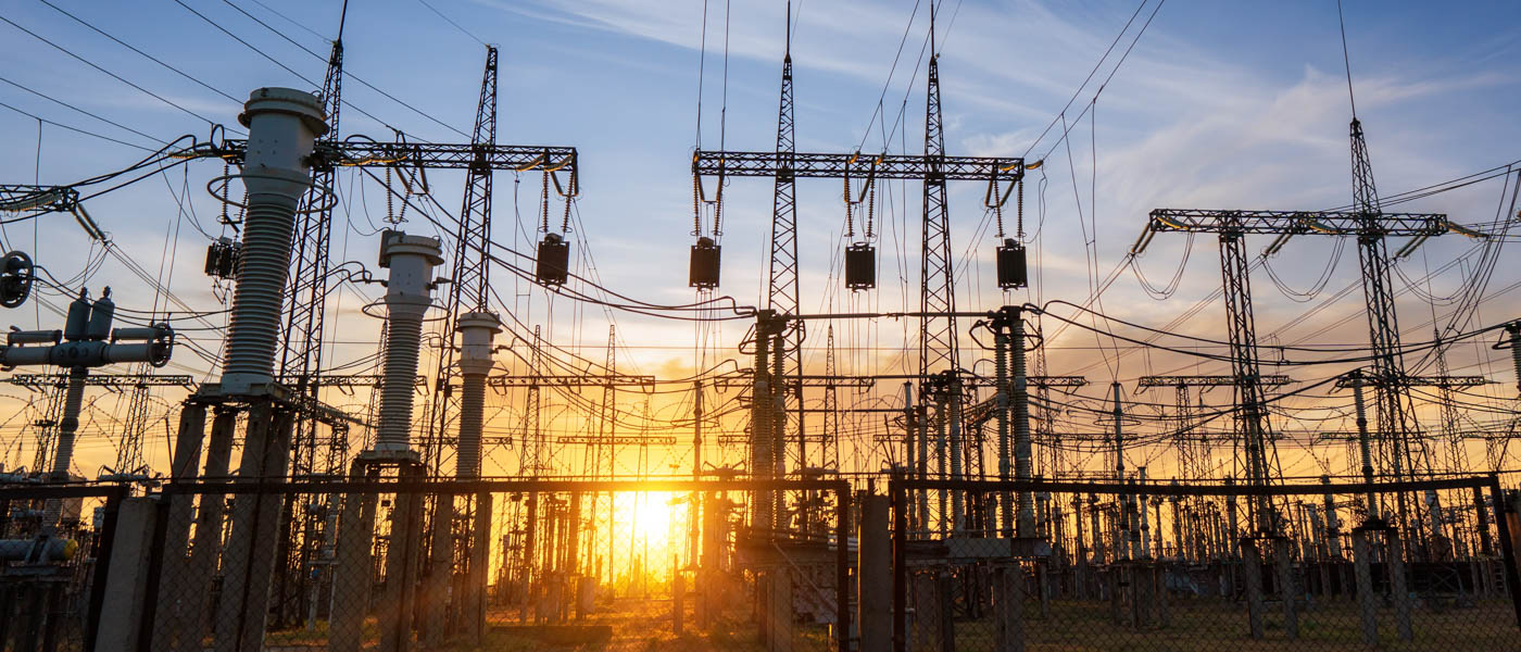 Power line pylons during sunset with beautiful blue sky.