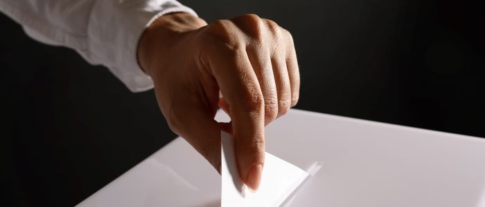 Photo of hand and ballot or suggestion box