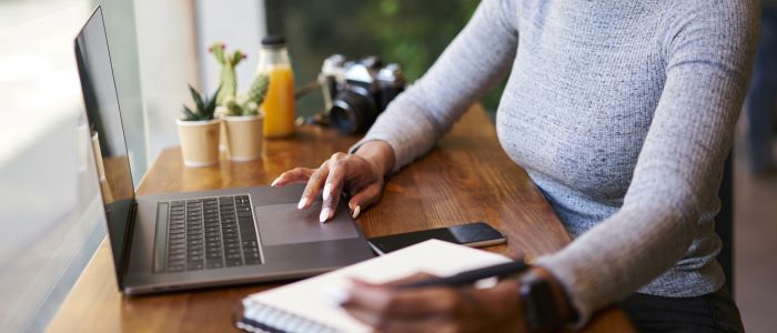 Photo of woman working on laptop with notepad and glass of orange juice