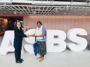 Dr Rayees Ahmad Sheikh and Dr Geethanjali Selvaretnam standing for a photo in front of giant 'ASBS' letters, in the Atrium of the Adam Smith Business School