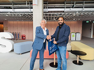 Professor Paton and Dr Ahmad Sheikh standing in front of giant 'ASBS' letters, in the Atrium of the Adam Smith Business School