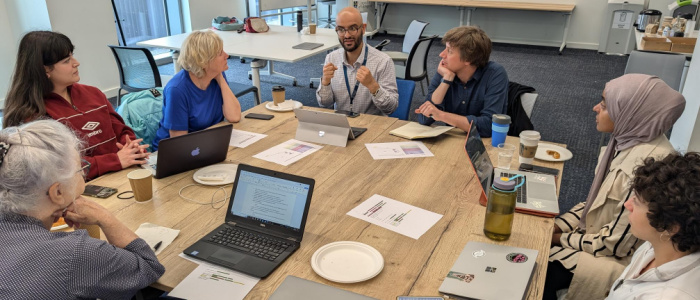 Image of a group of people sitting around a table discussing projects