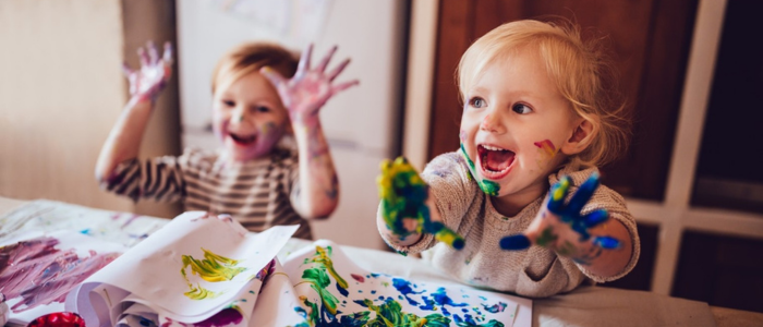 Two young children playing happily and messily with paints