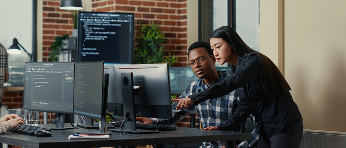 Two people pointing to and looking at a computer screen