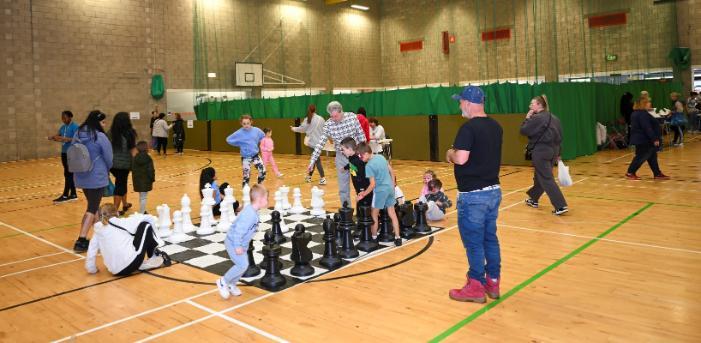 Children and adults playing giant chess in a sports hall