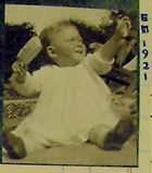 Photograph of Edwin Morgan as a baby in 1921. He is holding a hairbrush and reaching out with his other hand. (MS Morgan 917/1, page 228)