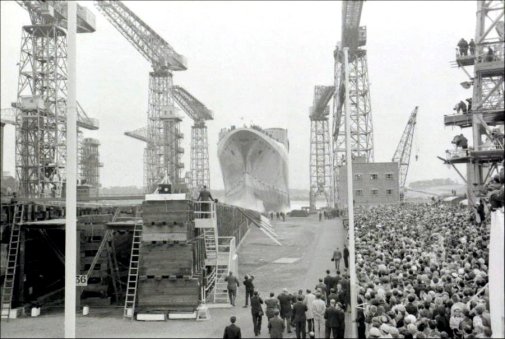 The QE2 is cheered by the crowds.