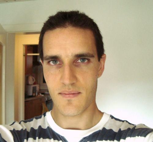 photograph of Salim Hirece: headshot of a mixed-race man with black short hair and stripy t-shirt, in a domestic setting