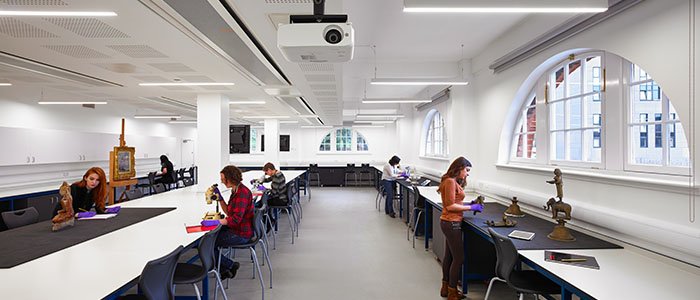 A large light room with students looking at different objects using microscopes