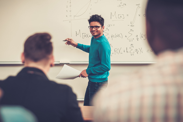 A students writes on a whiteboard in a class