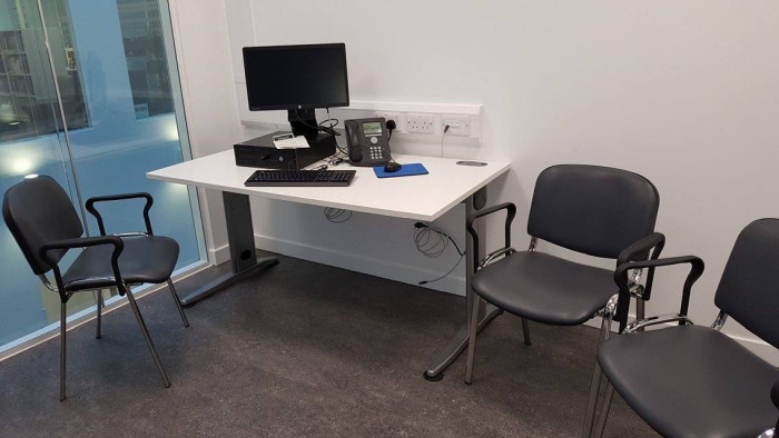 Flat floored interview room with chairs and desk with PC and telephone