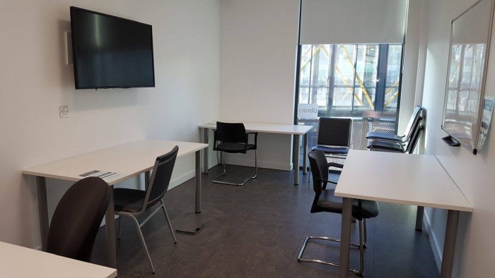 Flat floored training room with groups of tables and chairs, video monitor, and whiteboard