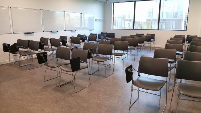 Flat floored teaching room with rows of tablet chairs and whiteboards