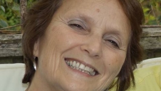 close-up photo of an older white woman with dark red hair, smiling broadly