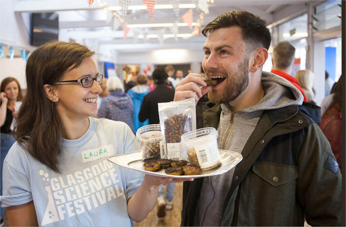 Photograph showing a GSF volunteer with a man who is tasting a bug.