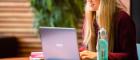 A smiling female student sitting at a laptop, studying