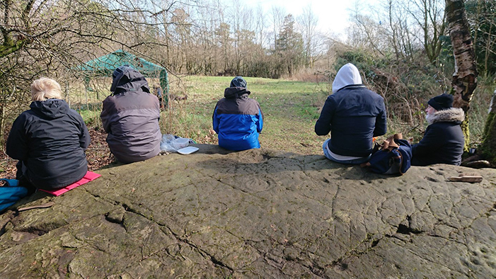 Scotland’s rock-art project survey training event in spring 2019. Five excavators have their lunch break on Auchnacraig 1 rock-art panel.