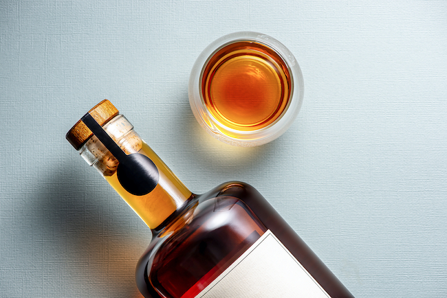 An image of an Everledger seal applied to the neck of a whisky bottle, lying next to a tumbler of whisky