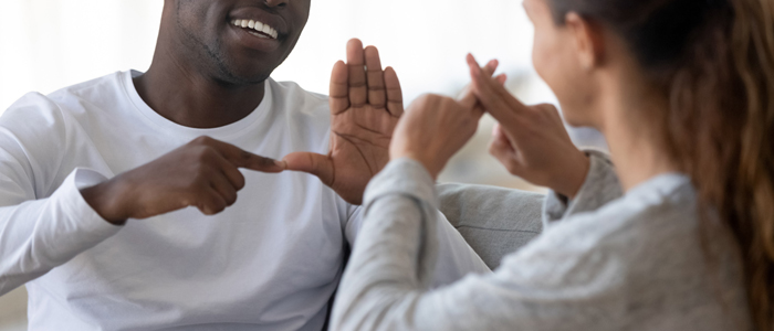 Photo of man and woman using BSL sign language