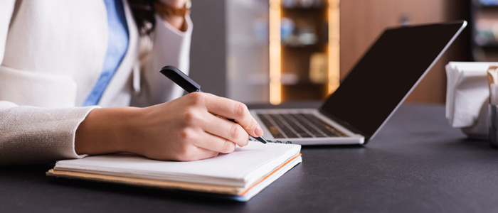 Photo of person with laptop, notepad and pen