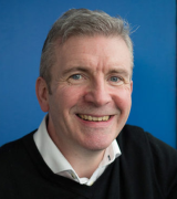 A head and shoulders shot of Professor Jonathan Cavanagh against a blue background