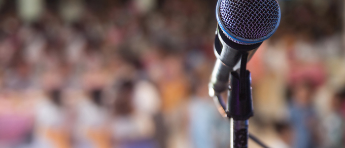 Photo of microphone with audience in background 