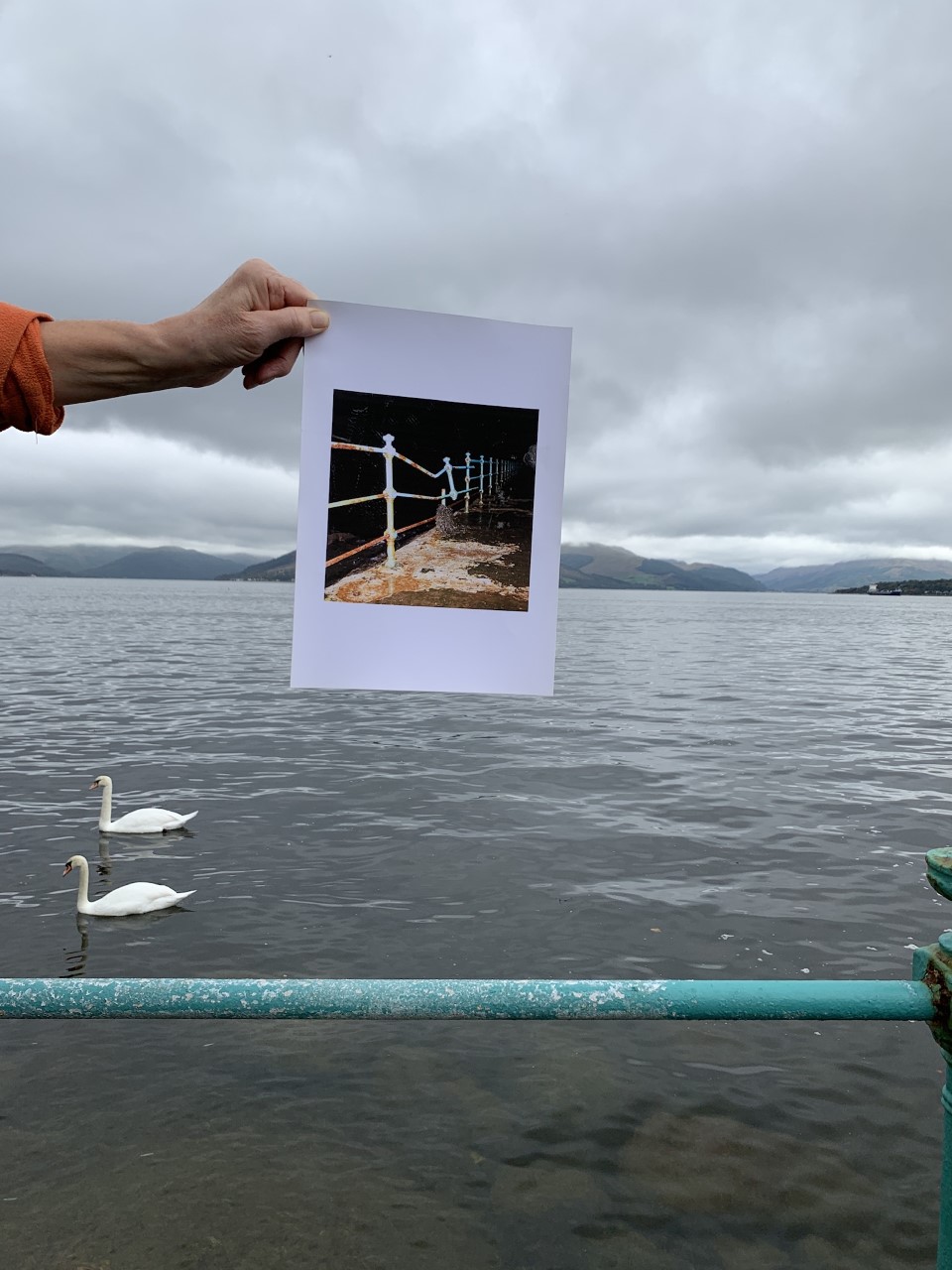 Photo of rusty railings held up by an arm next to the Clyde estuary