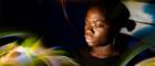 An  image of a woman sitting with her eyes closed surrounded by rainbow shafts of light. Image Credit Brenna Duncan 