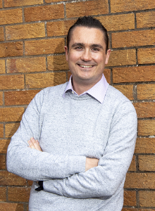 Student standing against brick wall at primary school placement