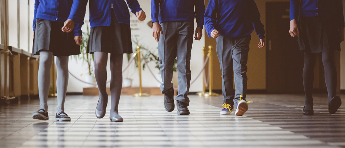 A row of students' legs walking down a hallway