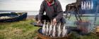 Image of a man smoking fish next to water