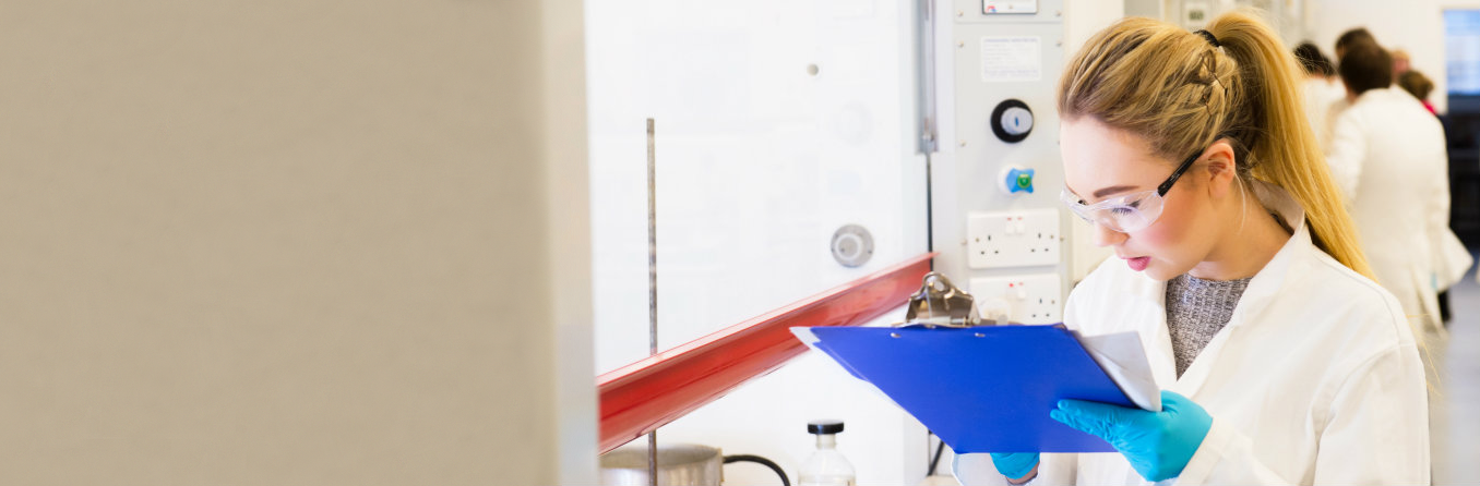 A staff member with clipboard marking down safety checklist in the laboratory