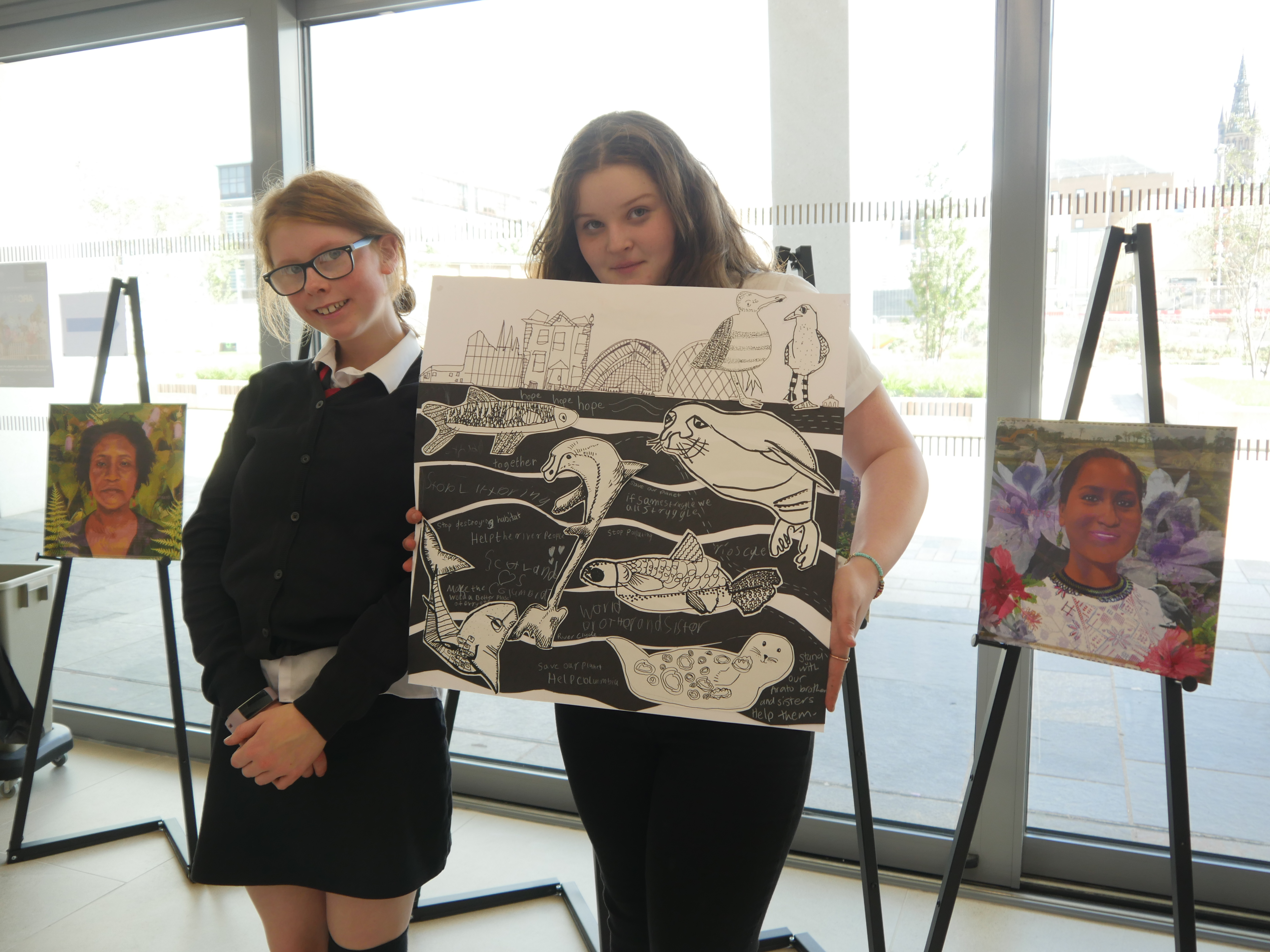 Two children holding artwork of a river