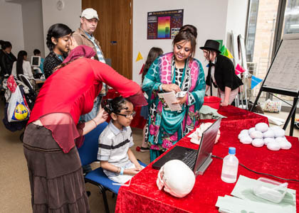 Photograph showing a child attached to a monitor. In front of her is models of the human skull and brain.