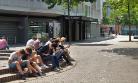 A group of high school students sit outdoors concentrating on their mobile phones