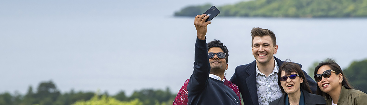 Students taking a group selfie with Dumfries hills and water behind them