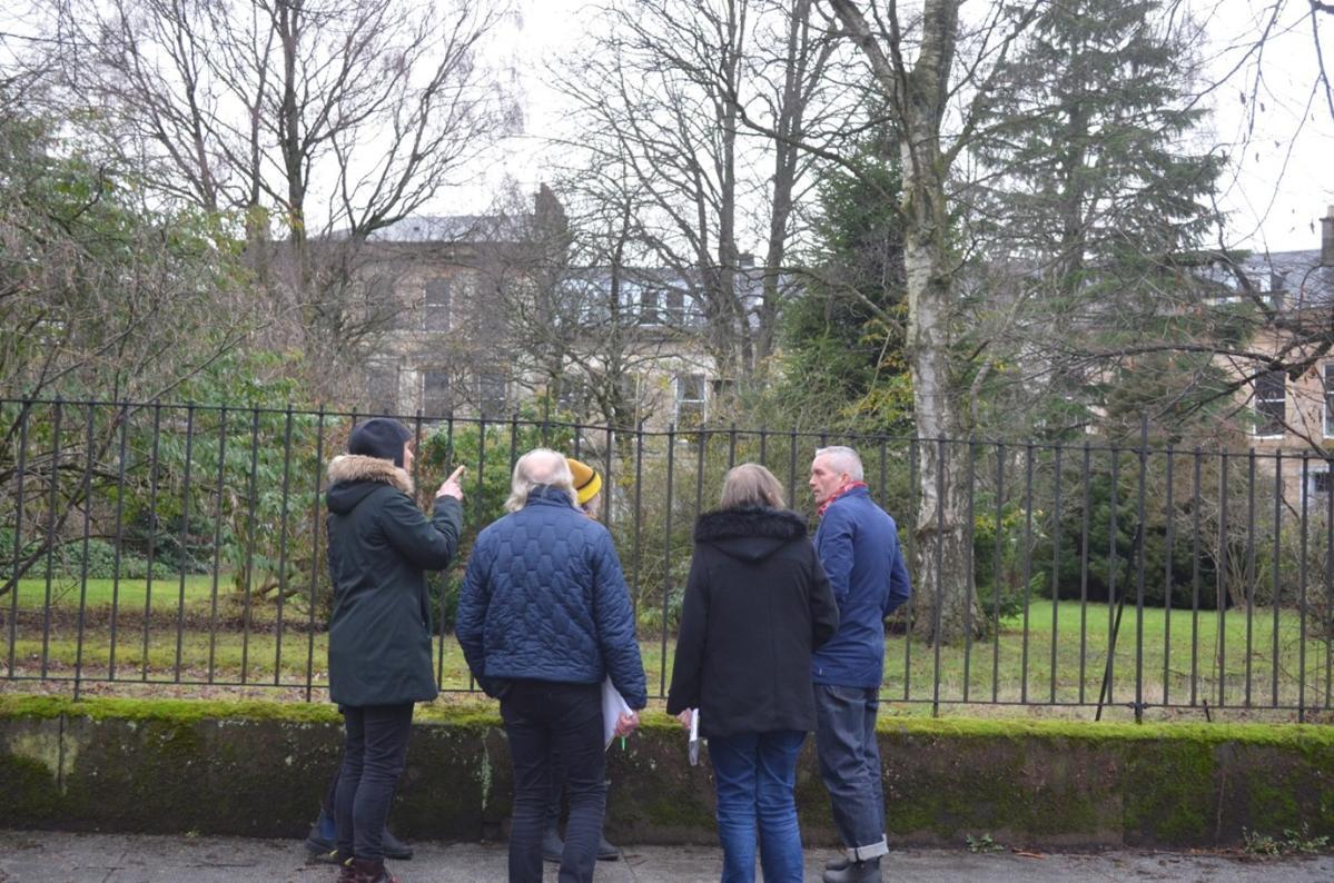 A photo of workshop participants gathered around the locked gate of a private garden