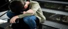 A teen sitting in despair, with a cell phone, head in his hands