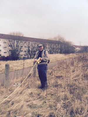 Photograph of a man holding one end of the measuring tape to set up the transect.